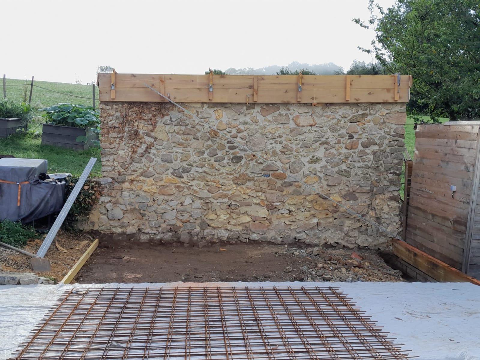 Préparation d’une dalle en béton devant un mur en pierre à Bergerac